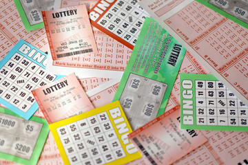 Many used lottery tickets, bills with numbers and bingo playing boards in big pile. Gambling and...