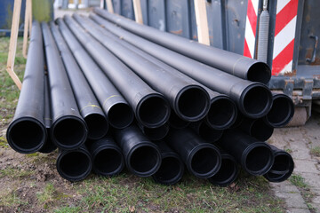 lot of new black pipes for protecting electrical wires lie on the ground, concept of repairing urban communications, conducting electrical networks, laying optical fiber for communication