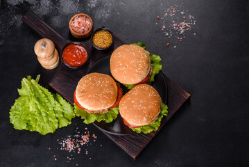 Three hamburger with beef meat burger and fresh vegetables on dark background