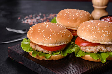 Three hamburger with beef meat burger and fresh vegetables on dark background