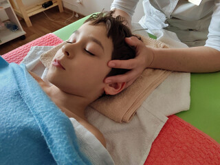 Obraz na płótnie Canvas osteopath does physiological and emotional therapy for kid. pediatric osteopathy treatment session. alternative medicine. taking care of the child's health.