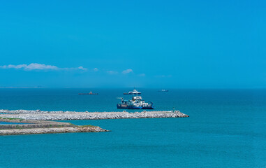 sea vessels and tugboats on the roadstead of the port against the background of breakwaters