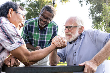 Group of senior friends playing arm wrestling at the park