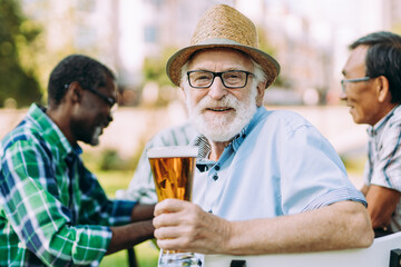 Group of senior friends drinking a beer at the park