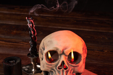 Humans skull with flame in its eyes and extinguished candles with smoke. Satanic ritual and wicca...