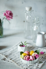 Fototapeta na wymiar Good morning. Delicious macarons desserts are served on the table in the morning for breakfast. Beautiful light still life with a rose highlight. Baking for breakfast on a light table with copy space
