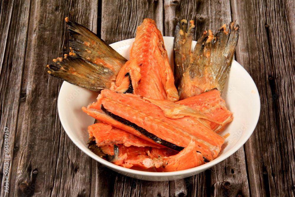 Wall mural Hot smoked salmon, trout bones, fork on white plate. Dark wooden board background.