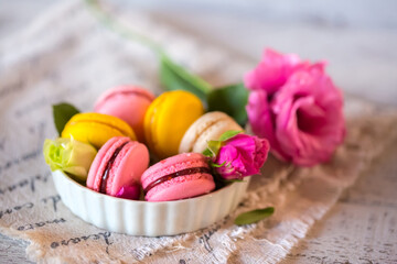 Obraz na płótnie Canvas Good morning. Delicious macarons desserts are served on the table in the morning for breakfast. Beautiful light still life with a rose highlight. Baking for breakfast on a light table with copy space
