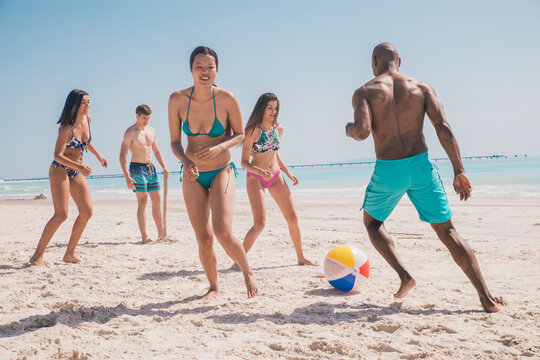 Group of friends spending time on the beach together celebrating. People enjoying the mediterranean sea and the nature. Concept about vacations and lifestyle