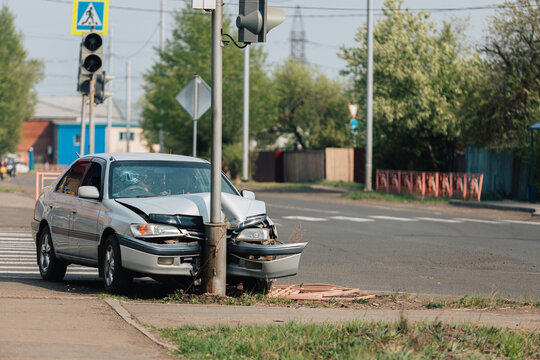 The car crashed into a pole at a crosswalk.