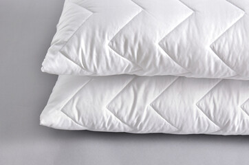 Stack of white soft pillows on gray background
