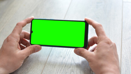 A man holds a smartphone with a green screen.Mockup. Copy space for text