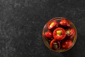 Red chilli stuffed with ricotta and capers in oil, top view, space for text, gray background