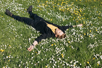 Young man laying in green grass with flowers. People fatigue from work. Summer sleeping and...