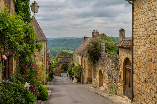 picturesque street with stone houses and blossoming flowers in the historic village of Domme in the Dordogne Valley