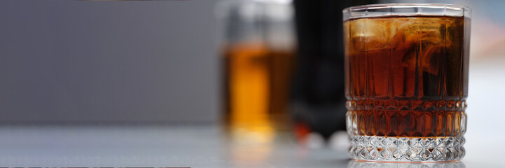 Full glass of alcoholic drink with ice on the table