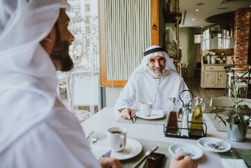 Three business men having a tea in Dubai wearing traditional emirati clothes
