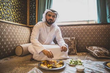 Arabic man with traditional clothes eating chicken mandy, in Dubai