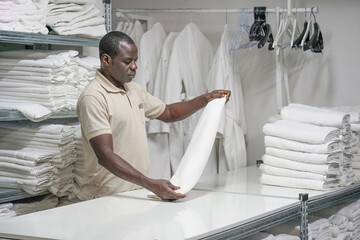 African hotel worker lays a clean white towel on the shelves. Hotel african american staff workers....