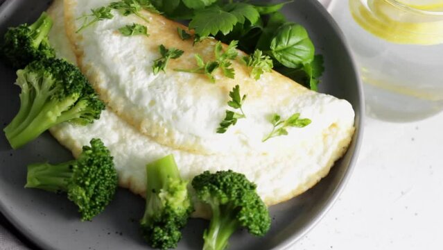 Protein omelet with broccoli and greens on a gray plate with lemonade.Healthy food concept. Rotate video