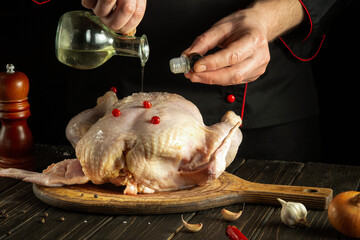 The chef adds vegetable oil to raw chicken. Cooking chicken in the kitchen with the hands of a cook