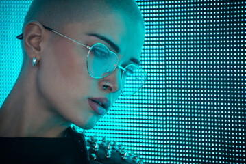 Image of a beautiful young woman posing against a led panel.