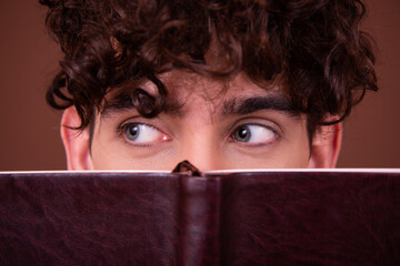 An attractive guy with beautiful eyes is reading a book.