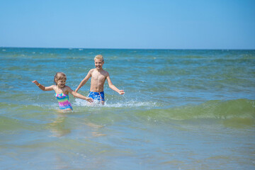 Girl and boy of having fun in water on beach and splashing