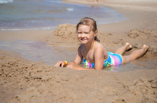 Happy child girl sitting on the beach 