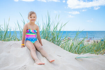 Happy child girl sitting on the beach 