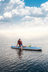 pretty girl wear Life vest is resting and sunbathing on a surfboard after training