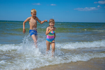 Girl and boy of having fun in water on beach and splashing