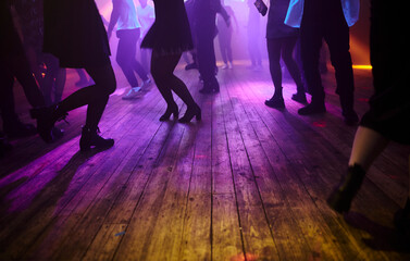 Dancing people on the dance floor. People are dancing, legs close up. Silhouettes of dancing people...
