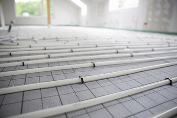 Shot of construction site in a loft where underfloor heating has just been installed, white pipes on grey mat