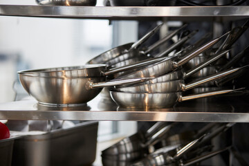 frying pans in a stack on a shelf 