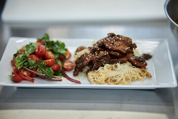 Asian noodles with beef and salad with fresh vegetables. 