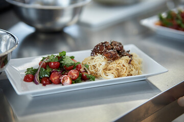 Asian noodles with beef and salad with fresh vegetables. 