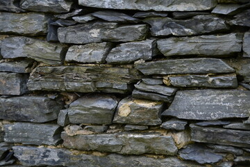 Fragment of an old stone wall. Large flat stones in the wall.