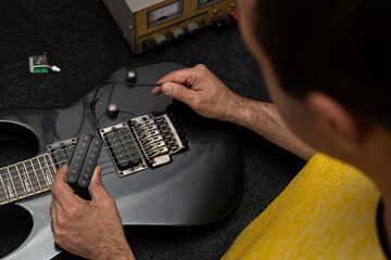 Latin American luthier holds in his hand the new microphone system of an electric guitar that will...