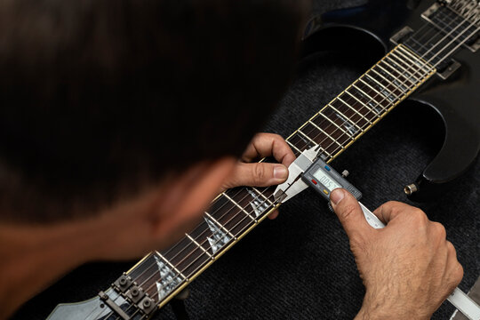 Latin American luthier calibrates the strings of an electric guitar with a digital vernier. Unrecognizable. Guitar concept, calibration, instrument.