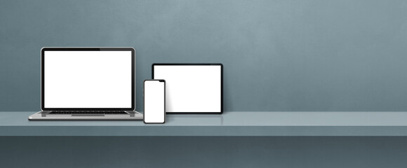 Laptop, mobile phone and digital tablet pc on grey wall shelf. Banner background