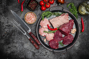 Different types of raw pork meat and beef on a dark background. various types of fresh meat pork and beef. Restaurant menu, dieting, cookbook recipe top view