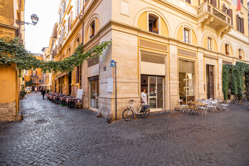 Fototapeta na wymiar Narrow street with cafe and small shops in Rome. Italy travel concept, visiting cozy places