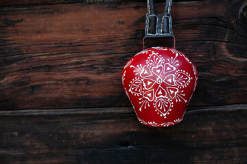 Traditional swiss cow bell red and white, decorative souvenir, on wooden background