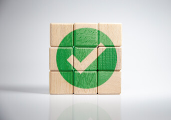 A check mark on a wooden block is placed on a white background.