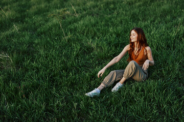 Young sportswoman warming up on the grass in the park on a sunny evening