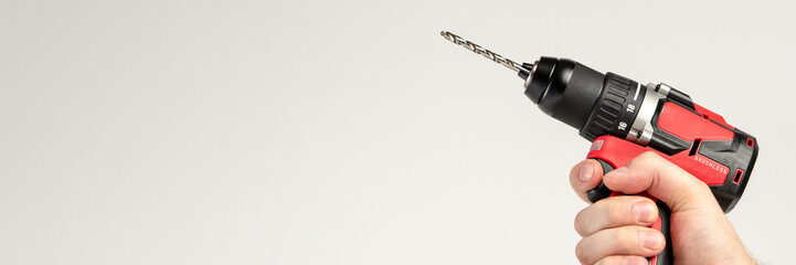 Cordless drill in black and red. Screwdriver with a drill in hand on a white background. Modern...