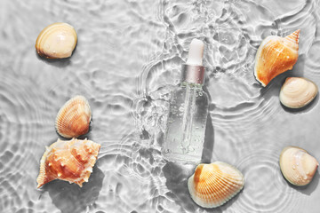 Organic cosmetic with sea minerals. Skincare cosmetic product and shells on gray water background