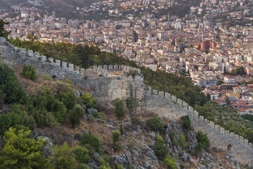 Obraz premium Turkey, Alanya, 30.08.2021: Wall fortress on the mountain and the city of Alanya from above. Landmark in Alanya, Turkey. Türkiye 