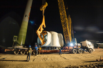 Tra Vinh, Vietnam - July 25 2021: Engineers operating crane to install the engine of a wind turbine tower to generate green energy and reduce global warming and climate change © Phuc